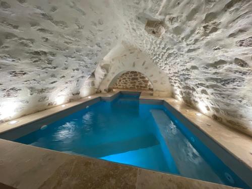 a swimming pool in a building with a stone wall at LE SPA INSOLITE DE MALAUCENE in Malaucène