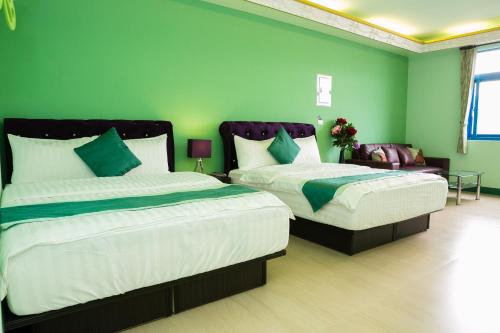 two beds in a room with green walls at 采蝶法拉民宿 in Xiaoliuqiu