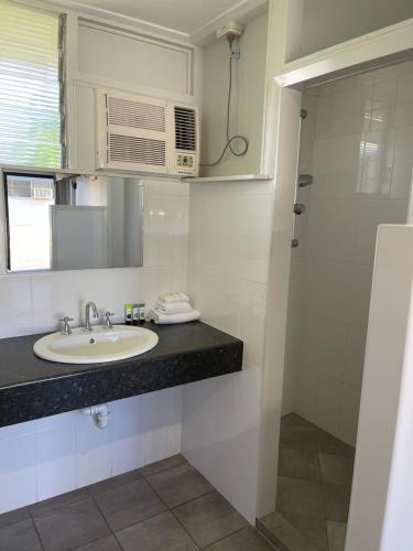 a bathroom with a sink, mirror, and toilet at Queens Beach Hotel in Bowen