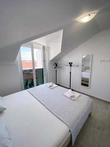 a white bedroom with a large bed and a mirror at Luminus Apartments in Srima