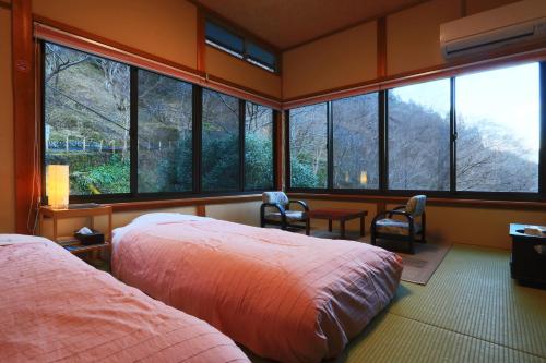 a bedroom with two beds and large windows at Miyoshino Sakuraan in Yoshino