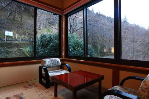 a room with a table and chairs and windows at Miyoshino Sakuraan in Yoshino