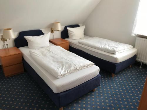 two beds in a room with two tables and two pillows at Hotel Hennies Hannover Sehnde in Hannover