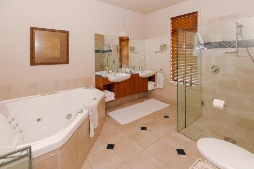 La salle de bains est pourvue d'une baignoire, de 2 lavabos et d'une douche. dans l'établissement Hiwinui Country Estate, à Palmerston North