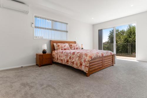 a bedroom with a bed and a large window at Picturesque Papamoa - Papamoa Holiday Home in Papamoa