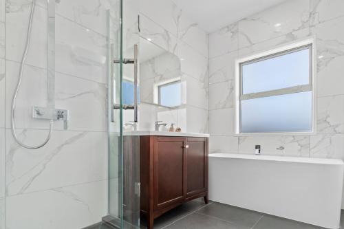 een badkamer met een douche, een bad en een wastafel bij Picturesque Papamoa - Papamoa Holiday Home in Papamoa