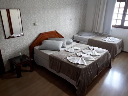 a bedroom with two beds with napkins on them at Pousada Cravo e Canela SJ in São Joaquim