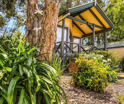 a yellow house with a tree and some plants at Nepean Shores by Gateway Lifestyle Holiday Parks in Penrith