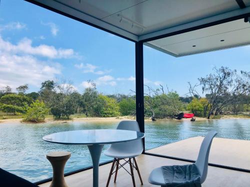 einen Tisch und Stühle vor einem Blick auf den Fluss in der Unterkunft oasis noosa - luxury floating eco villas in Noosa Heads