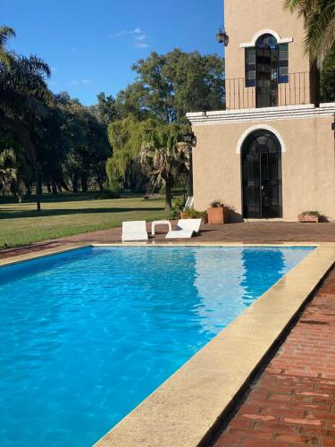 a swimming pool in front of a house at Don Aniceto - Suites de Campo in Luján