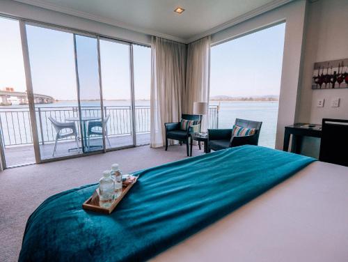 ein Hotelzimmer mit einem großen Bett und einem großen Fenster in der Unterkunft Trinity Wharf Tauranga in Tauranga