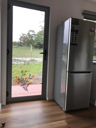 a refrigerator in front of a door with a window at Bicheno Wildflower Sands coastal retreat in Bicheno