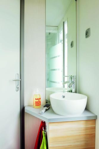 une salle de bain avec un lavabo et un miroir dans l'établissement Le Village Vacances de Mimizan Plage, à Mimizan-Plage
