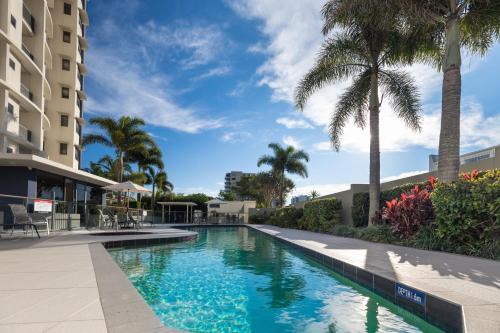 a swimming pool at a resort with palm trees at The Waterford Prestige Apartments in Caloundra
