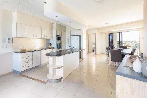 a large kitchen with white cabinets and a dining room at The Waterford Prestige Apartments in Caloundra