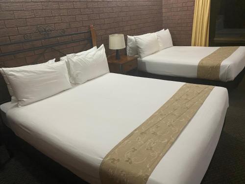 two beds in a hotel room with white sheets at Knotts Crossing Resort in Katherine