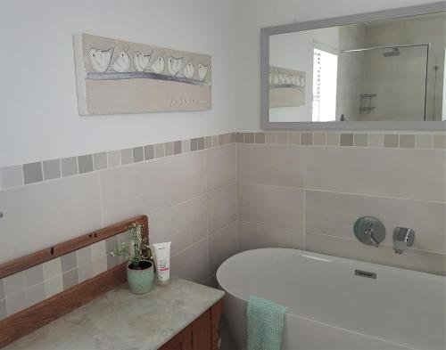 a white bathroom with a tub and a mirror at 16 Flame@ Supertubes, Luxury room, Jeffreys Bay in Jeffreys Bay