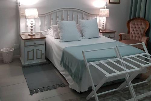 a bedroom with a white bed with two tables and a chair at 16 Flame@ Supertubes, Luxury room, Jeffreys Bay in Jeffreys Bay