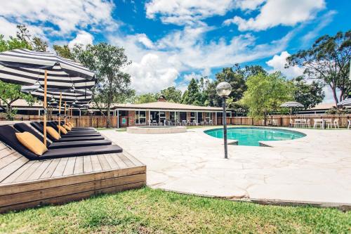 a patio with an umbrella and chairs and a pool at The Lodge Bellingen in Bellingen