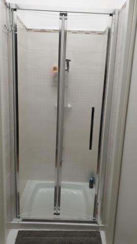La salle de bains est pourvue d'une douche avec une porte en verre. dans l'établissement Sotto le stelle, à Cursi