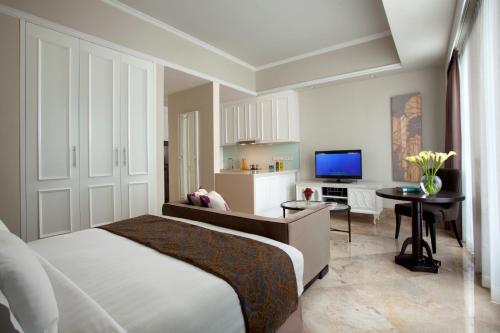 a bedroom with a bed and a desk and a television at Ascott Jakarta in Jakarta