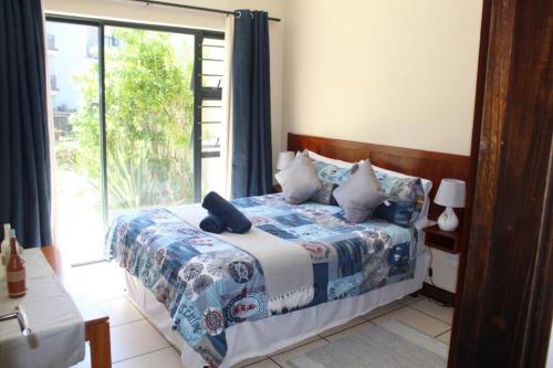 a bedroom with a bed and a large window at 7 Topanga in Uvongo Beach