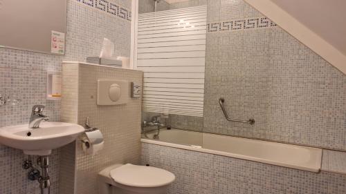 a bathroom with a sink and a toilet and a bath tub at Hotel La Passionaria in Mariánské Lázně