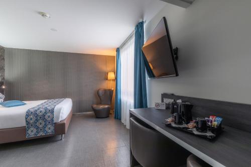 a hotel room with a bed and a tv on the wall at Mercure Bale Mulhouse Aeroport in Blotzheim