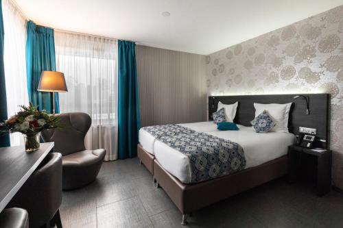a hotel room with a bed, desk and a lamp at Mercure Bale Mulhouse Aeroport in Blotzheim