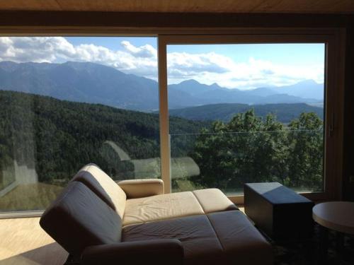 a living room with a couch in front of a large window at Südalpen Lofts in Bleiburg