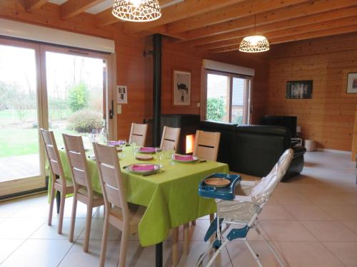 une salle à manger avec une table et des chaises vertes dans l'établissement Gîte Autre Ruche, à Baudement