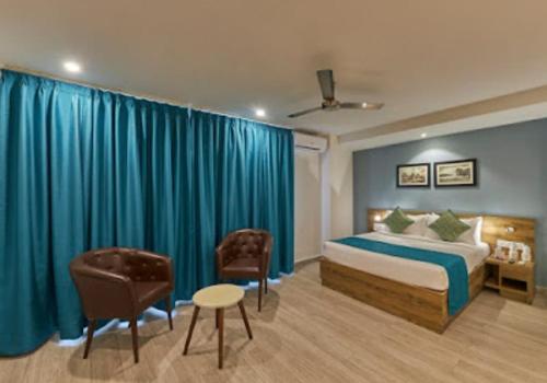 バンガロールにあるRegenta INN Grand Koramangala by Royal Orchid Hotelsのベッドと椅子付きのホテルルーム