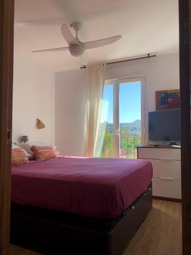 a bedroom with a bed with a ceiling fan and a window at Ático a 200m del mar. in Jávea