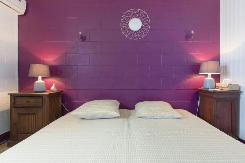 a bedroom with a purple wall and a bed with two lamps at Villa élégante à Saint-Paul avec piscine privée ouverte toute l'année in Saint-Paul