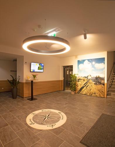 a large lobby with a clock on the floor at OEKOTEL Hohenems in Hohenems