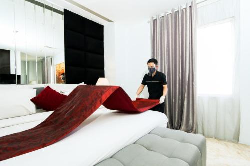 a man standing in a bedroom with a large bed at Gino Feruci Braga by KAGUM Hotels in Bandung