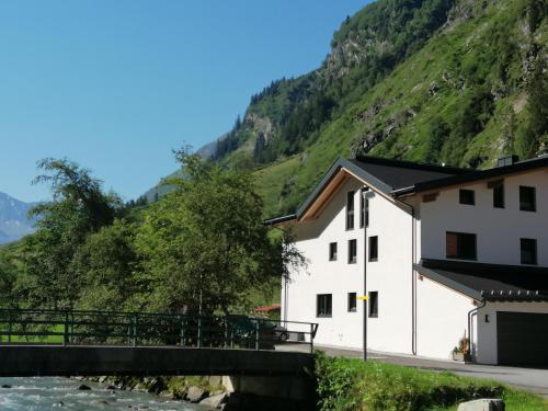 ein weißes Gebäude mit einer Brücke neben einem Berg in der Unterkunft Haus Larcher Appartment in Sankt Leonhard im Pitztal