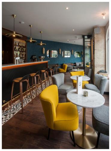 a restaurant with yellow chairs and tables and a bar at Hotel André Latin in Paris
