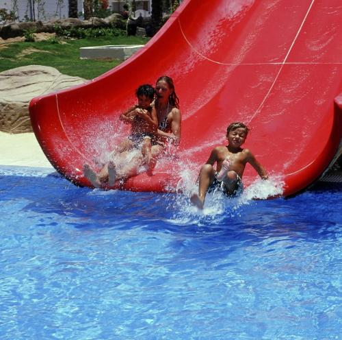 a group of children playing on a red slide in the water at Sharm Dreams Vacation Club - Aqua Park in Sharm El Sheikh
