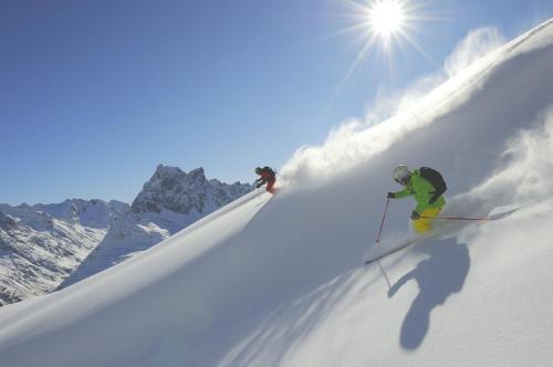 two people skiing down a snow covered mountain at Hotel Schwarzer Adler in Pettneu am Arlberg
