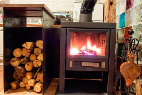 a stove with a fire in it next to a pile of logs at Casa Rural El Cuco in Robledillo