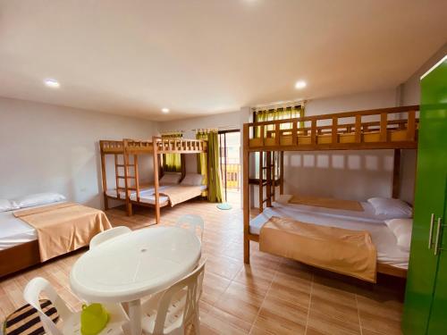 a room with three bunk beds and a table at Cerca Parola Beach Resort in Malabrigo