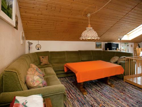 ein Wohnzimmer mit einem grünen Sofa und einem Tisch in der Unterkunft Restful Holiday Home near Ski Lift in Petersthal in Oy-Mittelberg