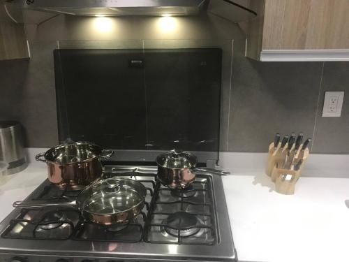 a stove top with three pots on top of it at Luxury house with all the amenities Gym Seg Aa cal Pool Tv Wifi in Querétaro