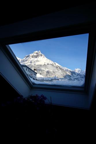 a view of a snow covered mountain through a window at ALP APARTMENTS centre location with traditional design and self check-in in Engelberg