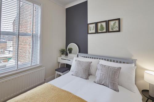 1 dormitorio con cama blanca y ventana en Host & Stay - Fountains Cottage, en Guisborough