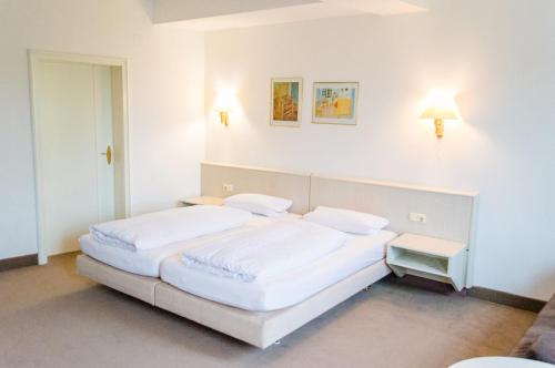 a bedroom with two beds and two lights on the wall at Hotel Goldner Stern in Königsberg in Bayern