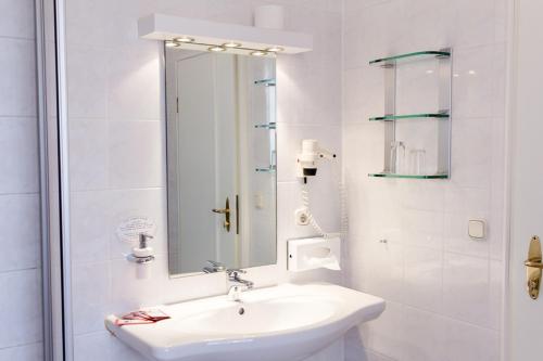 Baño blanco con lavabo y espejo en Hotel Goldner Stern, en Königsberg in Bayern