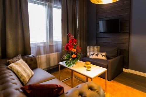 ein Wohnzimmer mit einem Sofa und einem Tisch mit Blumen in der Unterkunft Hotel Golden Circle Suites in Rovaniemi