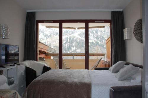 - une chambre avec un lit et une grande fenêtre dans l'établissement Beau deux pièces Isola 2000, à Isola 2000